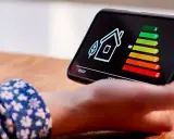 Écran de smartphone affichant une maison et un barème d'efficacité énergétique. La question "une clim consomme plus en chaud ou froid" est implicite.