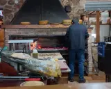 Un hombre trabaja en la cocina del restaurante Emilio Riopar, cerca de un jamonero y un horno de leña.