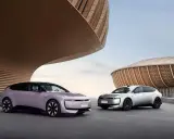 Deux Audi E5 Sportback, une lilas et une argentée, se présentent devant des bâtiments aux formes organiques.