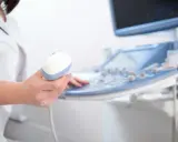 Lekarz trzyma sondę aparatu USG, przygotowując się do badania echo serca. Prawidłowe parametry echo serca są kluczowe dla diagnozy.
