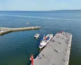 Ludzie czekają na rejsy z Krynicy Morskiej. Statek "Anita" zacumowany przy molo, obok mniejsze łodzie.