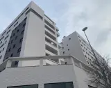 Modernas viviendas VPO en Alicante, edificios de ladrillo blanco y gris con balcones, bajo un cielo nublado.