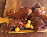 Delicioso cochinillo al horno, crujiente y jugoso, servido con patatas asadas sobre tabla de madera.
