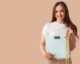 Femme souriante tenant une balance et un mètre ruban, prête à perdre 10 kilos.