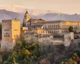 Die Alhambra in Granada, ein Traumziel nach einer Reise von Sevilla. Majestätische Festungsmauern und Paläste vor schneebedeckten Bergen.