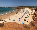 Sonniger Tag am playa fuente del gallo mit vielen bunten Sonnenschirmen und Badegästen im türkisfarbenen Meer.