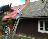 Pracownicy w kombinezonach zabezpieczających usuwają eternit z dachu. To pokazuje, co to jest azbest i jak wygląda jego utylizacja.