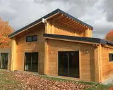 Une belle maison en bois, prête à accueillir ses habitants. L'automne arrive, les feuilles tombent autour de cette construction chaleureuse.