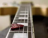 Médiator sur le manche d'une guitare, prêt à jouer une gamme arabe.