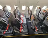 Puste fotele w samolocie Pegasus Airlines, gotowe na odprawę pasażerów. Czerwone pasy bezpieczeństwa czekają.