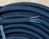 Gaine électrique bleue enroulée, prête pour une installation dans le jardin. Trois fils colorés (rose, jaune, bleu) émergent de son extrémité, suggérant la profondeur de son utilité.