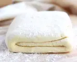 Pâte feuilletée prête à être utilisée pour votre recette. Les couches sont bien visibles, saupoudrées de farine.