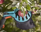 Un sécateur à fruits attrape une pomme rouge, facilitant la tâche de recueillir les fruits des branches hautes.