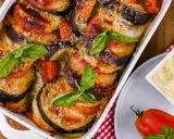 Gebackene Auberginen-Tomaten-Schichten in Auflaufform, garniert mit Basilikum. Perfekt, um Auberginen haltbar zu machen und köstlich zu genießen.