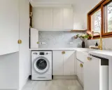 Lavanderia piccola moderna con lavatrice, lavello bianco, rubinetto dorato e finiture eleganti. Ottime idee per sfruttare ogni spazio.