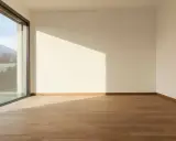Habitación vacía con suelo de madera y gran ventanal de cristal planitherm que ofrece vistas a montañas.
