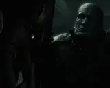 Potworna twarz Nemesisa z Resident Evil w mroku, groźnie spogląda na Claire.