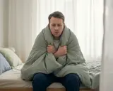 Man med feber och frossa, insvept i filt. Kan vara malaria symtom.