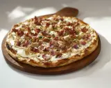 Flammekueche garnie d'oignons et de lardons, un accompagnement parfait pour un repas convivial.