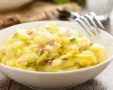 Schüssel mit cremigem Kartoffelsalat, garniert mit roten Zwiebeln und Schnittlauch. Ein köstliches Rezept für Kartoffelsalat!