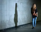 Dziewczyna z plecakiem idzie przez tunel, jej cień na ścianie symbolizuje dyfuzję odpowiedzialności.