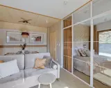 Przytulne pokoje i apartamenty Wierchy Zakopane. Salon z sofą i widokiem na sypialnię z łóżkiem, w góralskim stylu.