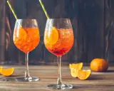 Dwa orzeźwiające drinki Aperol Spritz, idealne, by dowiedzieć się, jak zrobić pomarańczowy. Z plastrem pomarańczy i słomką.