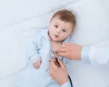 Lekarz osłuchuje dziecko z objawami RSV. Dowiedz się, jak leczyć RSV u niemowląt i dzieci.