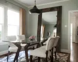 Un grand miroir rustique reflète la salle à manger, offrant une idée de où mettre un miroir dans une salle à manger pour agrandir l'espace.