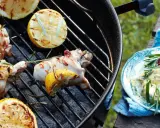 Grillad kyckling med citron och rosmarin på grillen, redo att serveras med en krämig röra och chili.