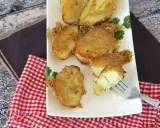 Krispiga, gyllene bitar av confiterad potatis, perfekt tillagade och serverade på en vit tallrik med en gaffel som visar den mjuka insidan.