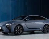 El elegante Lexus ES 2026, un sedán azul metálico, se exhibe contra una pared azul texturizada.