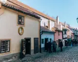 Urokliwa, brukowana złota uliczka w Pradze, z kolorowymi domkami i turystami spacerującymi pośród nich.