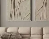Deux tableaux texturés, style diy tableau relief, aux tons sable, accrochés au-dessus d'un canapé beige.