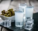 Trzy kieliszki z mlecznym ouzo, kostki lodu i miseczka oliwek. Tak pije się ouzo, by poczuć smak Grecji.