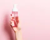 Mano sostiene botella de agua micelar con dispensador. ¡Perfecto para cuando el agua micelar se enjuaga!
