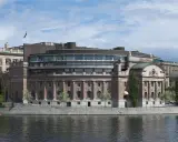Riksdagshuset i Stockholm, en symbol för sveriges statsskick, med sin moderna glasdel och klassiska stenfasad vid vattnet.