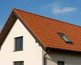 Nowy bungalow z pomarańczowym dachem i oknem dachowym, gotowy na słoneczne dni.