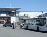Autobus wahadłowy na lotnisko Oslo Torp. Ludzie z bagażami wychodzą z terminala.
