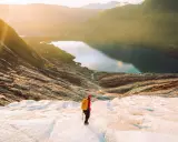 Vandrare på en glaciär i Norge med en sjö och berg i bakgrunden. En av många norge sevärdheter.
