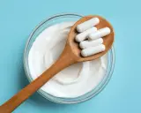 Cuillère en bois avec des gélules blanches sur un yaourt crémeux. Une question se pose : quel probiotique pour maigrir ?