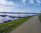 Jezioro Pogoria 4 z łodziami przy pomoście i ścieżką rowerową.