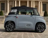 Une petite voiture grise, un ami pour la ville, se gare devant un bâtiment imposant.