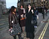 Un elegante cappotto a vestaglia nero, indossato con disinvoltura, si abbina perfettamente a un look audace e moderno.