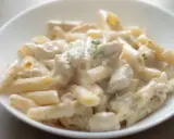 Penne z kremowym sosem i kawałkami kurczaka, udekorowane gałązką ziół. Pyszna potrawka z kurczaka w sam raz na obiad.