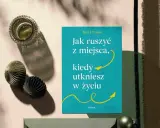 Książka "Jak ruszyć z miejsca, kiedy utkniesz w życiu" Britt Frank. Obok szklanka z napojem i ozdobne kule. Idealna lektura, gdy dopada lenistwo.