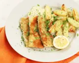 Krispigt friterad zucchini med pommes frites, en klick sås och en citronskiva.