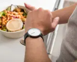 Mann schaut auf seine Uhr, neben einer Schüssel mit Salat. Die Frage: darf man fasten wenn man krank ist?