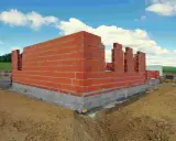 Budowa domu w toku: wznoszone ściany z cegły, fundamenty gotowe. Czas pokaże, ile trwa budowa domu.