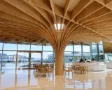 Interno moderno con soffitto in legno curvo, un esempio di architettura giapponese. Tavoli e sedie in legno, vista sul mare.